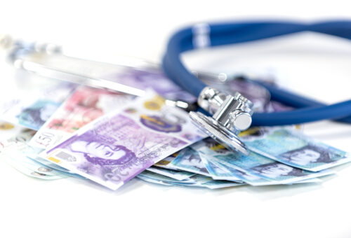 A stethoscope on top of a pile of Sterling notes