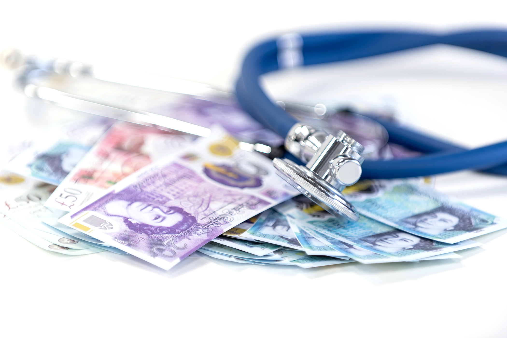 A stethoscope on top of a pile of Sterling notes