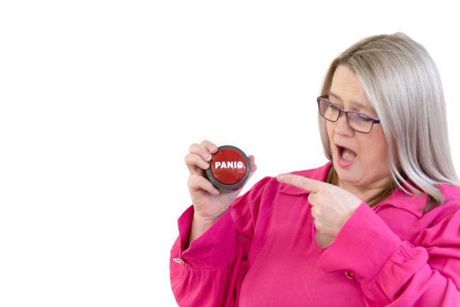 Nicki holding a big red button that says "Panic"