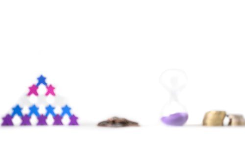 A blurred image showing a pyramid of meeples, metal cogs, an hourglass, and stacked coins, symbolising a lack of clarity around team roles, systems, time, and cash flow