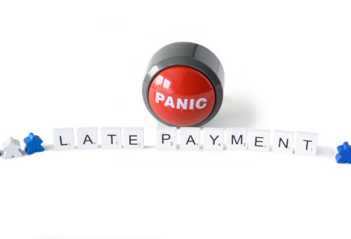 Panic button and the words late payment spelled out in wooden tiles.