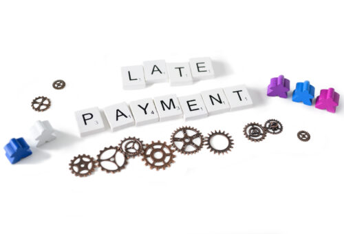 Late Payment written out in letter times with cogs to represent processes and meeples to represent people.